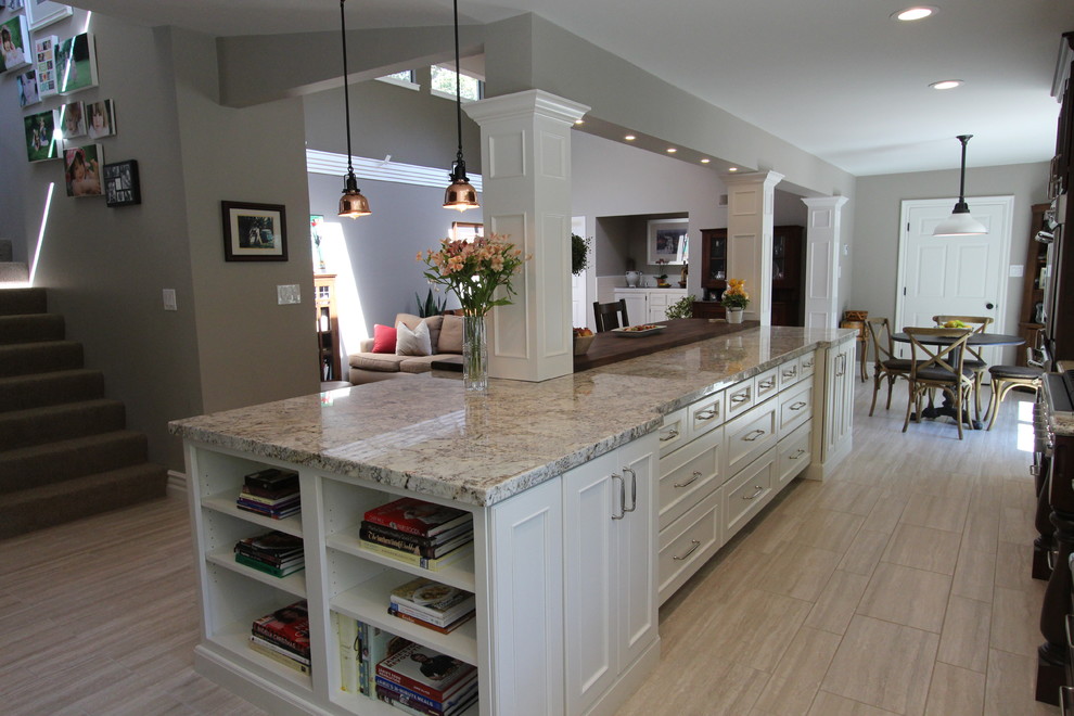 This is an example of a mid-sized country l-shaped eat-in kitchen in San Francisco with a farmhouse sink, recessed-panel cabinets, dark wood cabinets, granite benchtops, white splashback, subway tile splashback, panelled appliances, porcelain floors and with island.