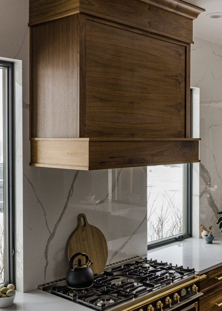 Inspiration for a mid-sized transitional l-shaped light wood floor and brown floor eat-in kitchen remodel with a farmhouse sink, shaker cabinets, blue cabinets, quartz countertops, white backsplash, quartz backsplash, black appliances, an island and white countertops