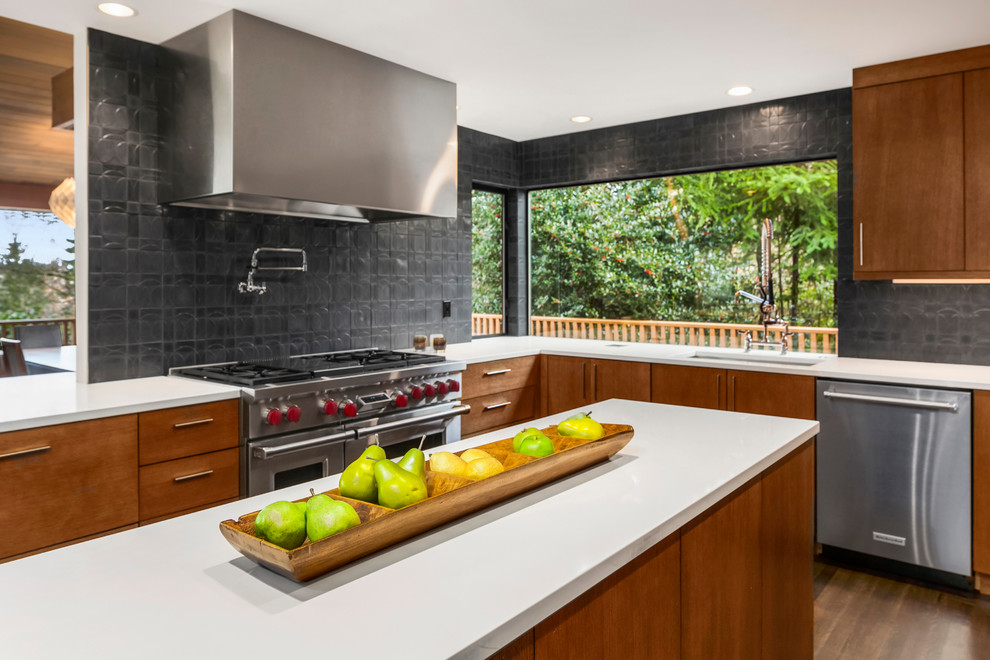 Photo of a large midcentury u-shaped open plan kitchen in Seattle with an undermount sink, flat-panel cabinets, light wood cabinets, quartz benchtops, black splashback, cement tile splashback, stainless steel appliances, medium hardwood floors and with island.