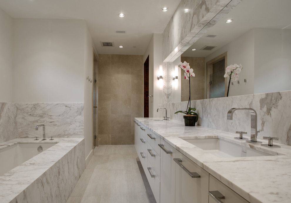 Design ideas for a large modern master bathroom in Dallas with an undermount sink, flat-panel cabinets, white cabinets, marble benchtops, an undermount tub, a curbless shower, a one-piece toilet, white tile, stone tile, white walls and limestone floors.