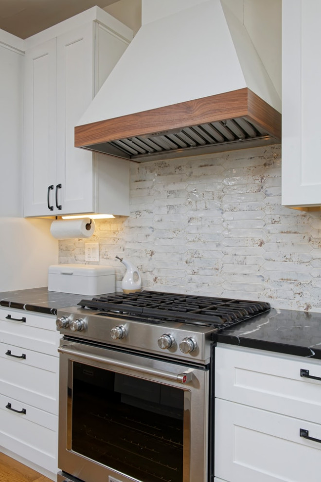 Esempio di una cucina classica di medie dimensioni con lavello sottopiano, ante in stile shaker, paraspruzzi bianco, elettrodomestici in acciaio inossidabile, pavimento in legno massello medio e top nero