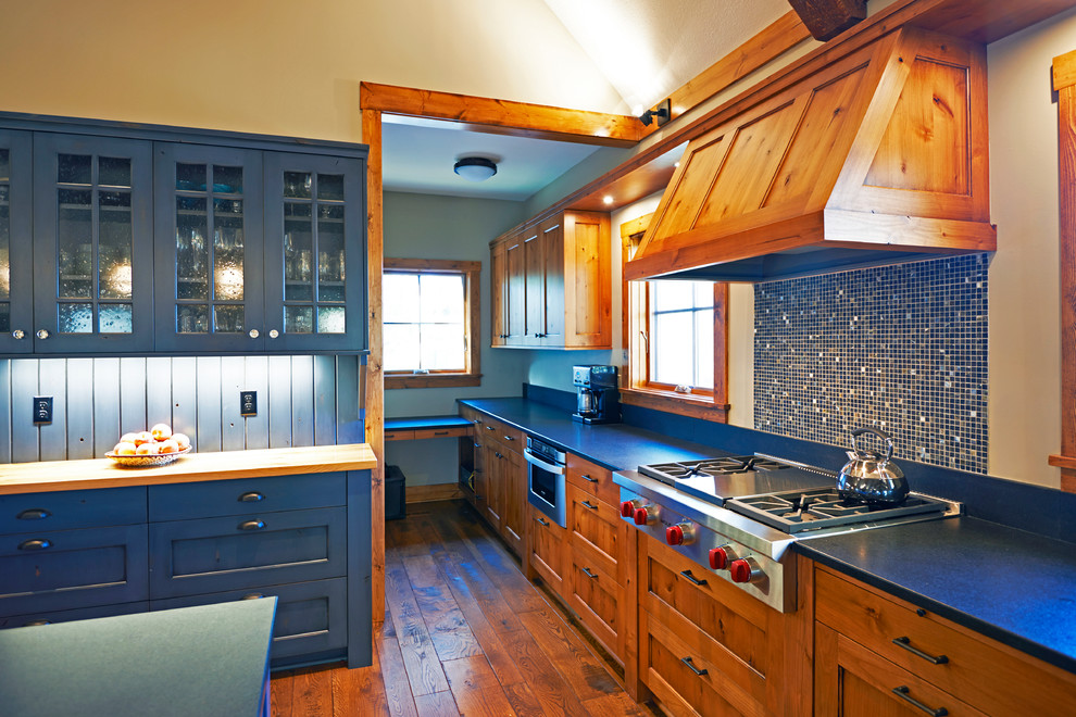 Photo of a mid-sized country u-shaped open plan kitchen in Minneapolis with a farmhouse sink, beaded inset cabinets, blue cabinets, soapstone benchtops, blue splashback, mosaic tile splashback, panelled appliances, medium hardwood floors and with island.
