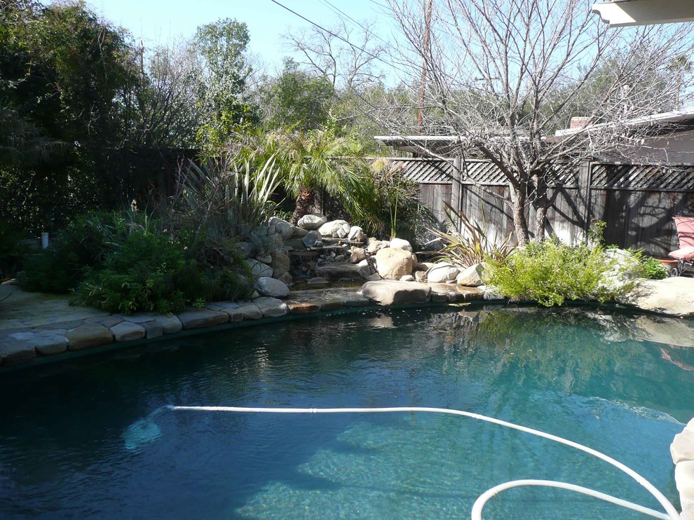This is an example of a mid-sized traditional backyard kidney-shaped natural pool in Santa Barbara with a water feature and natural stone pavers.