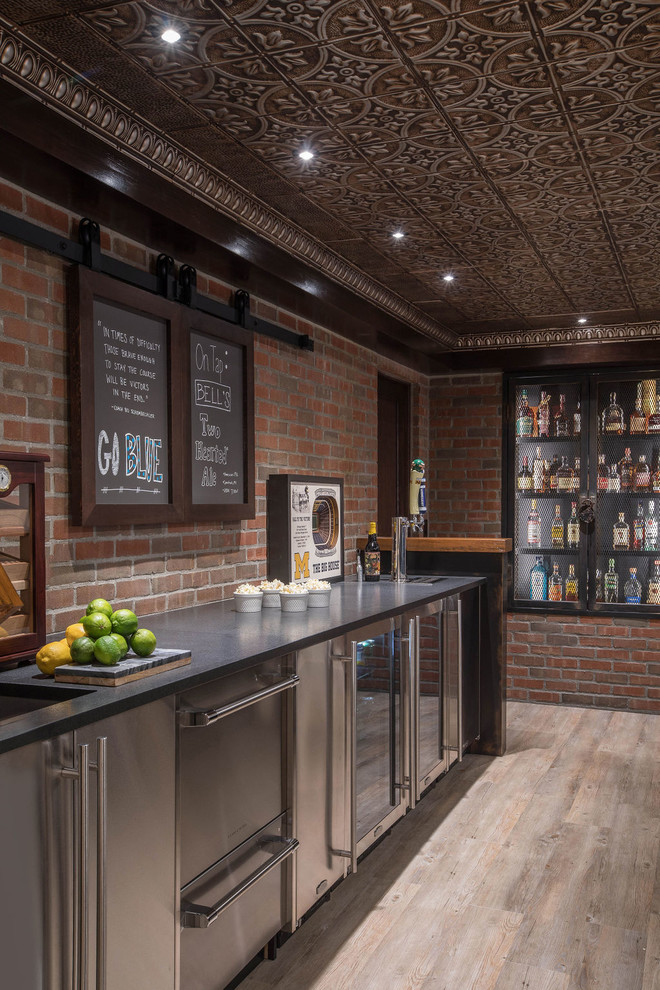 Photo of a large industrial galley seated home bar in Detroit with vinyl floors, beige floor, an undermount sink, black cabinets, wood benchtops, red splashback, brown benchtop and brick splashback.