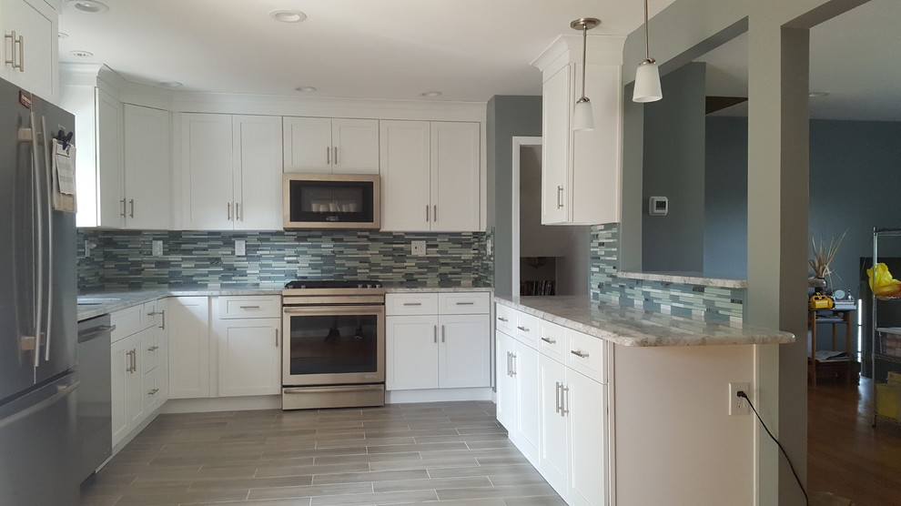 This is an example of a mid-sized modern kitchen in New York with an undermount sink, shaker cabinets, white cabinets, quartzite benchtops, blue splashback, glass sheet splashback, stainless steel appliances, porcelain floors and grey floor.