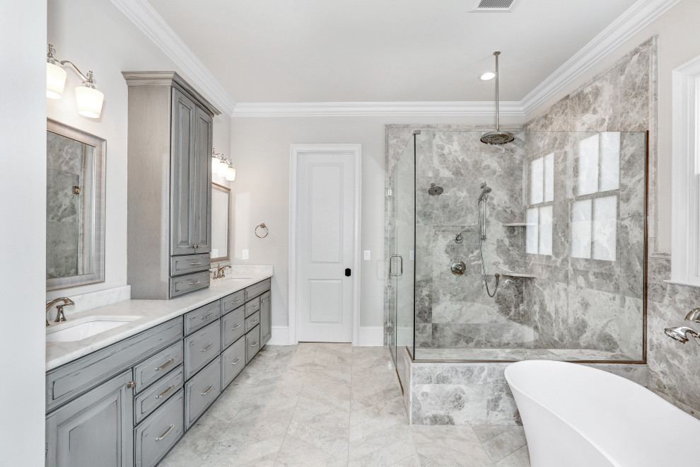 Inspiration for a transitional master gray tile and white tile marble floor, gray floor and double-sink freestanding bathtub remodel with raised-panel cabinets, distressed cabinets, gray walls, an undermount sink, marble countertops, a hinged shower door, white countertops and a built-in vanity