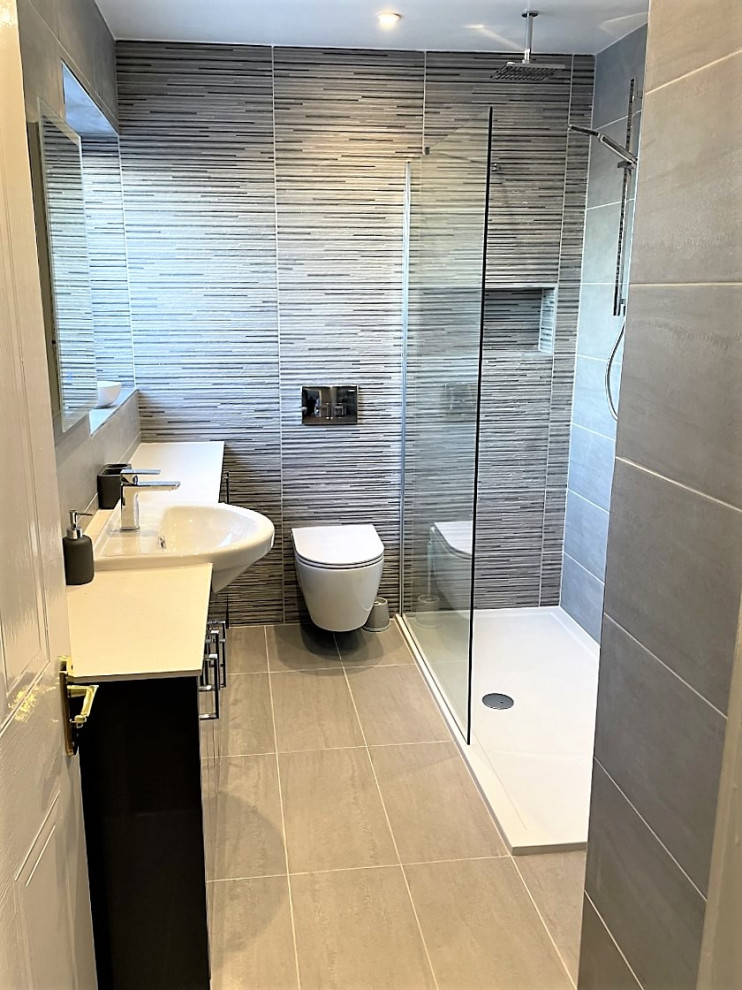 This is an example of a mid-sized modern kids bathroom in Other with flat-panel cabinets, grey cabinets, an open shower, a wall-mount toilet, gray tile, porcelain tile, porcelain floors, a drop-in sink, laminate benchtops, grey floor, an open shower, white benchtops, a niche, a single vanity and a built-in vanity.