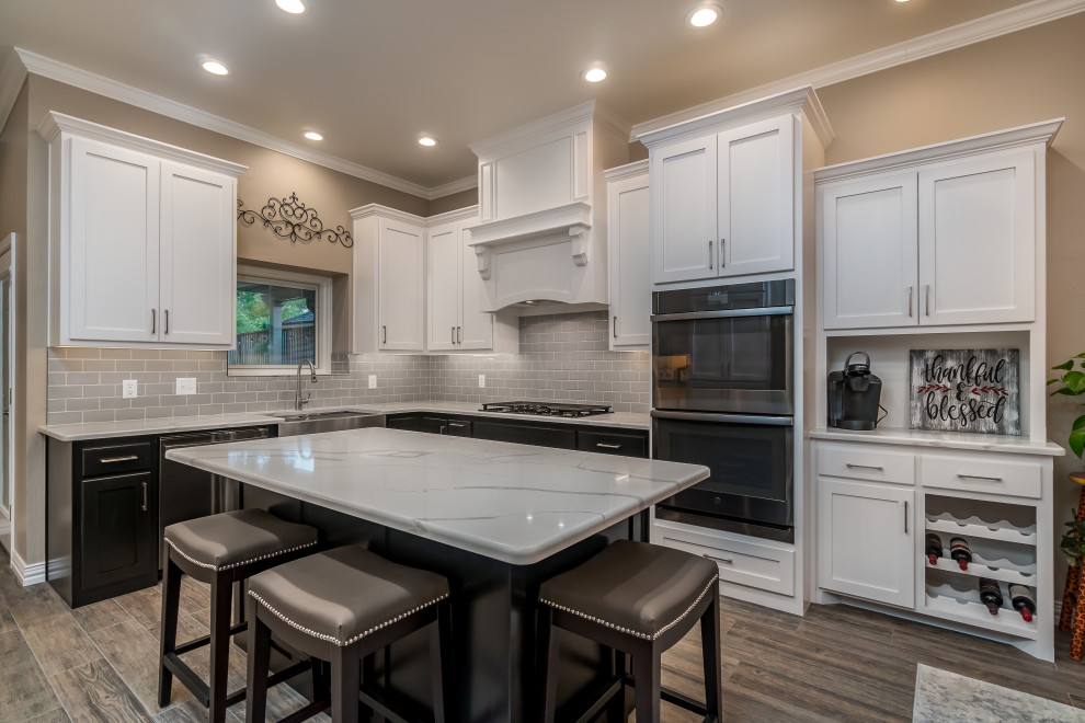 Inspiration for a contemporary u-shaped ceramic tile and gray floor eat-in kitchen remodel in Other with a farmhouse sink, recessed-panel cabinets, quartz countertops, gray backsplash, ceramic backsplash, black appliances, an island and white countertops
