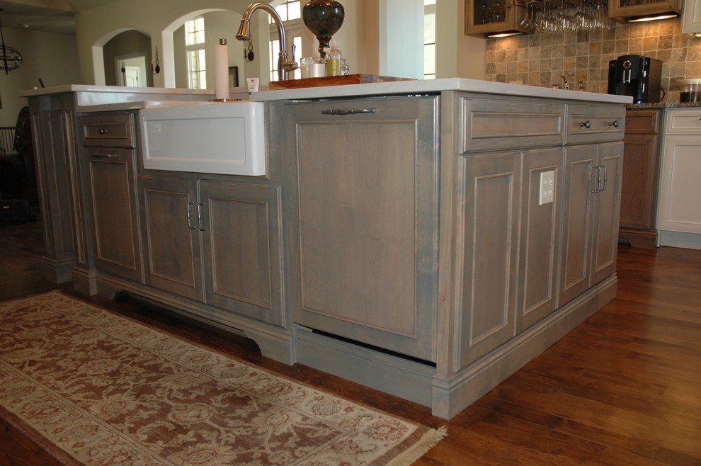 Example of a large transitional u-shaped medium tone wood floor kitchen pantry design with a farmhouse sink, flat-panel cabinets, yellow cabinets, laminate countertops, brown backsplash, stone tile backsplash, paneled appliances and an island