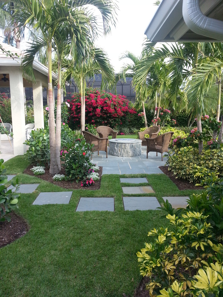 Tropical patio in Miami with a fire feature and natural stone pavers.