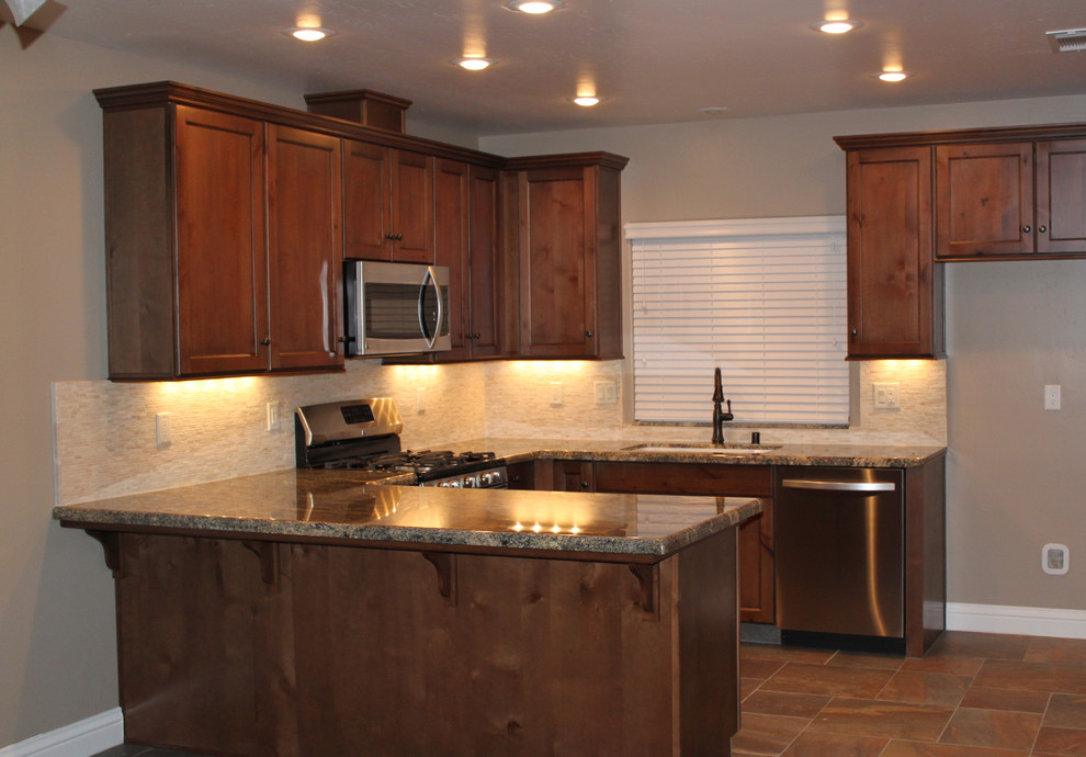 Inspiration for a mid-sized transitional u-shaped slate floor and brown floor kitchen remodel with an undermount sink, shaker cabinets, medium tone wood cabinets, granite countertops, white backsplash, stone tile backsplash, stainless steel appliances and a peninsula