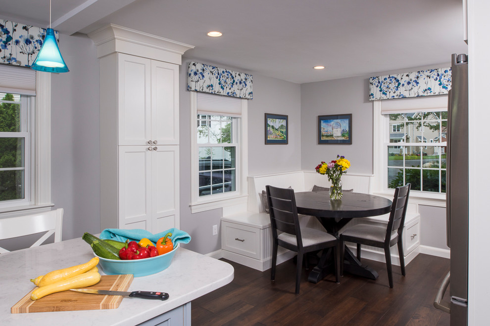 Transitional l-shaped dark wood floor and brown floor kitchen photo in Boston with a farmhouse sink, flat-panel cabinets, white cabinets, quartz countertops, white backsplash, ceramic backsplash, stainless steel appliances and an island