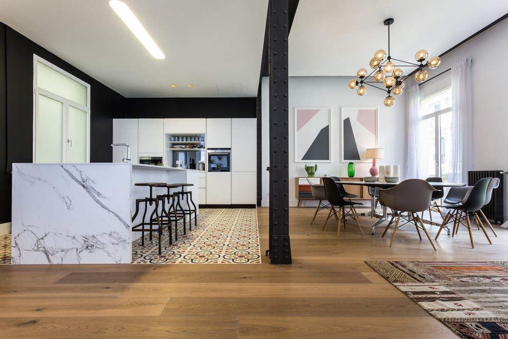 This is an example of a large contemporary single-wall open plan kitchen in Madrid with an undermount sink, flat-panel cabinets, white cabinets, medium hardwood floors and with island.