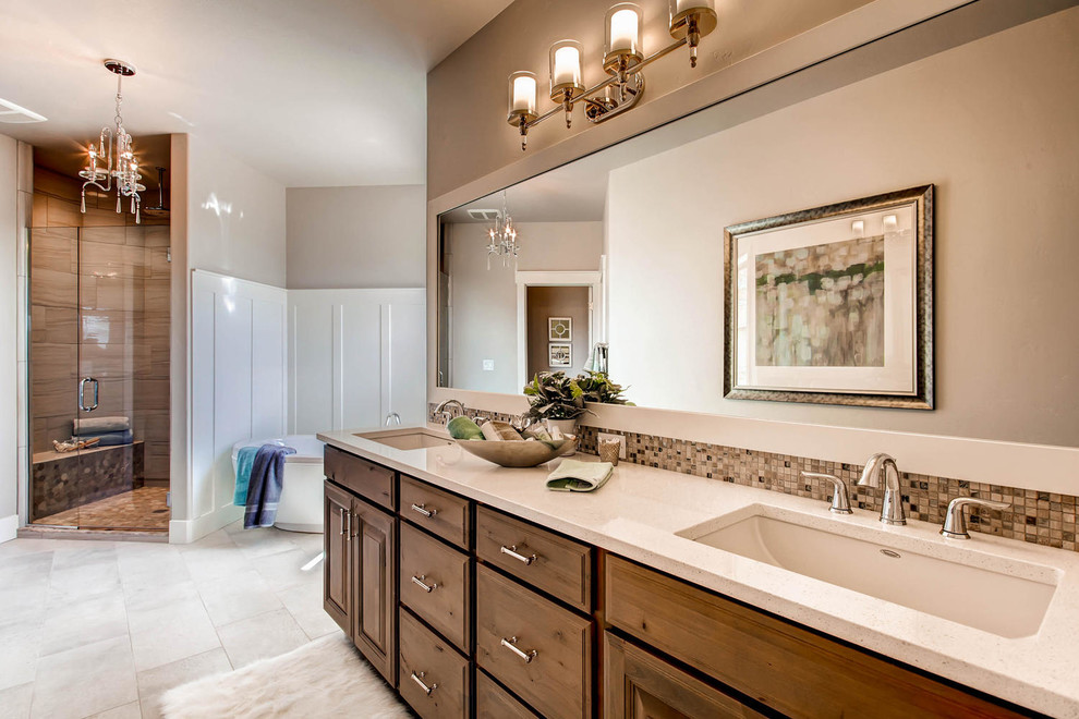 This is an example of a large traditional master bathroom in Denver with raised-panel cabinets, medium wood cabinets, a freestanding tub, an alcove shower, gray tile, beige walls and ceramic floors.