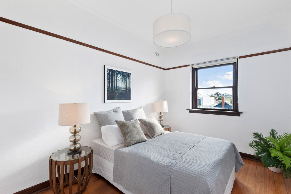 Inspiration for a mid-sized contemporary guest bedroom in Melbourne with white walls, medium hardwood floors and brown floor.