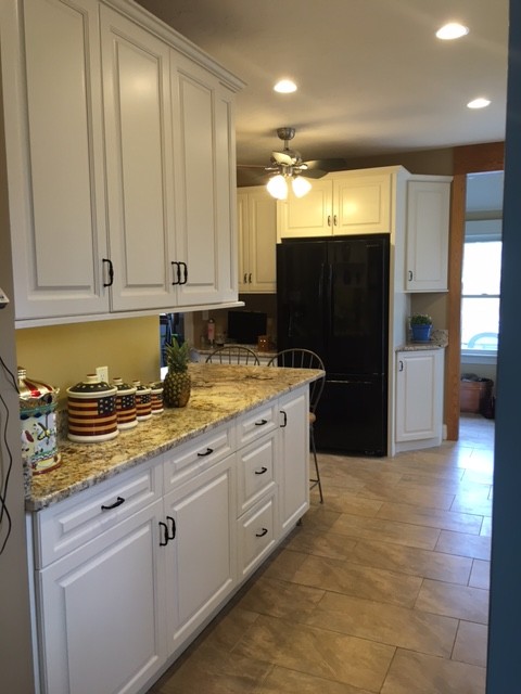 Example of a mid-sized transitional galley porcelain tile eat-in kitchen design in Boston with an undermount sink, raised-panel cabinets, white cabinets, granite countertops, black appliances and an island