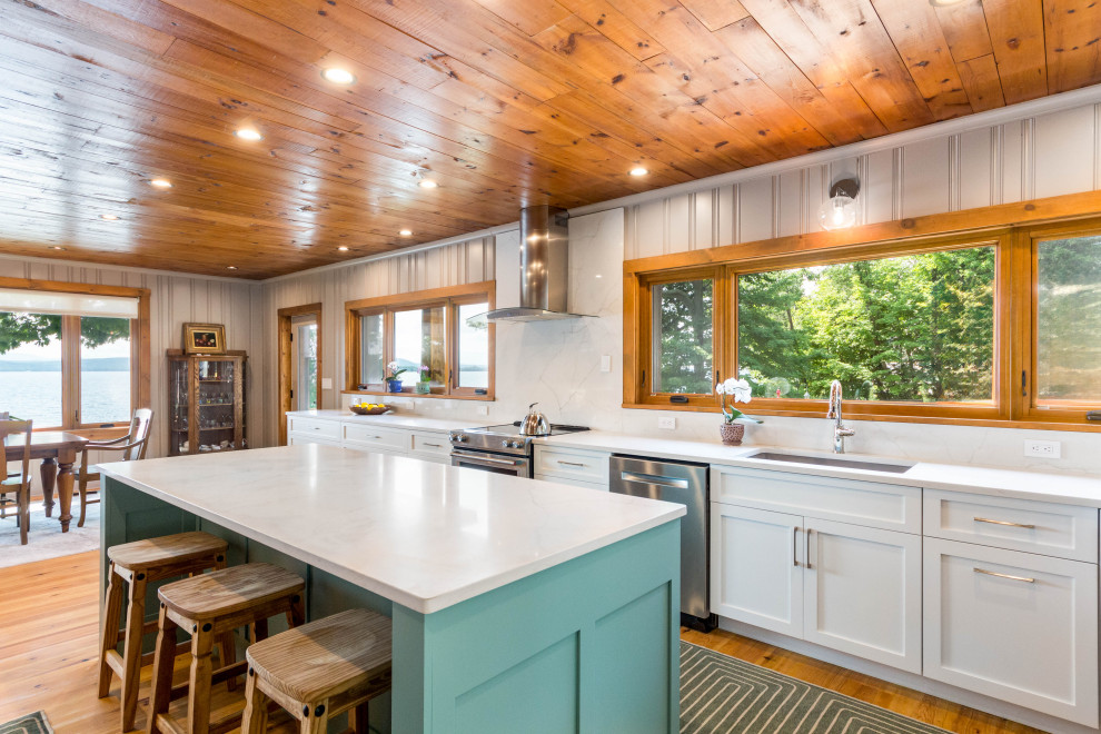 Inspiration for a transitional medium tone wood floor, orange floor and wood ceiling eat-in kitchen remodel in Burlington with an undermount sink, shaker cabinets, white cabinets, quartz countertops, white backsplash, quartz backsplash, stainless steel appliances, an island and white countertops