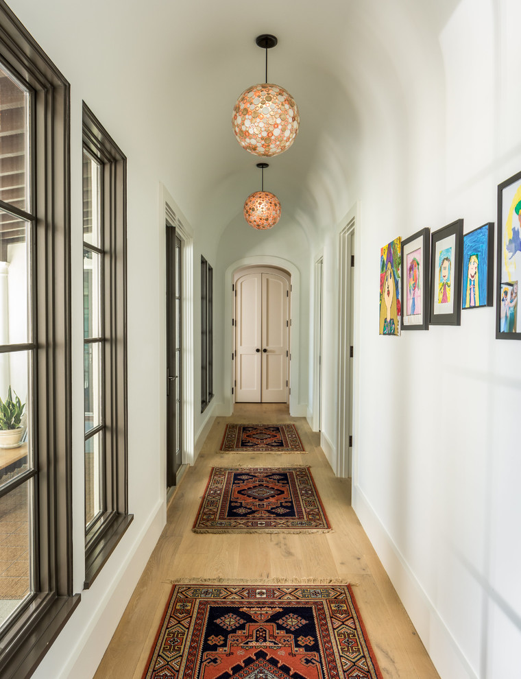 Design ideas for a mediterranean hallway in Charleston with white walls, light hardwood floors and beige floor.