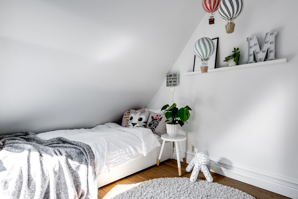 Inspiration for a scandinavian kids' bedroom in Stockholm with white walls, medium hardwood floors and brown floor.