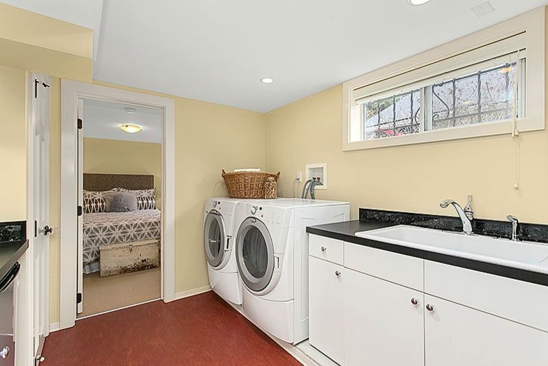 This is an example of a mid-sized arts and crafts galley laundry cupboard in Seattle with a drop-in sink, flat-panel cabinets, quartz benchtops, linoleum floors, a side-by-side washer and dryer, white cabinets and beige walls.