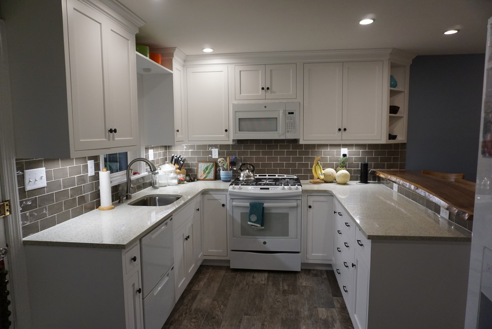 Mid-sized traditional u-shaped eat-in kitchen in Philadelphia with an undermount sink, shaker cabinets, white cabinets, granite benchtops, grey splashback, subway tile splashback, white appliances, laminate floors, a peninsula and brown floor.