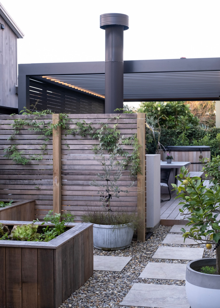 Photo of a contemporary side yard full sun garden in Auckland with a vegetable garden, river rock and a wood fence.