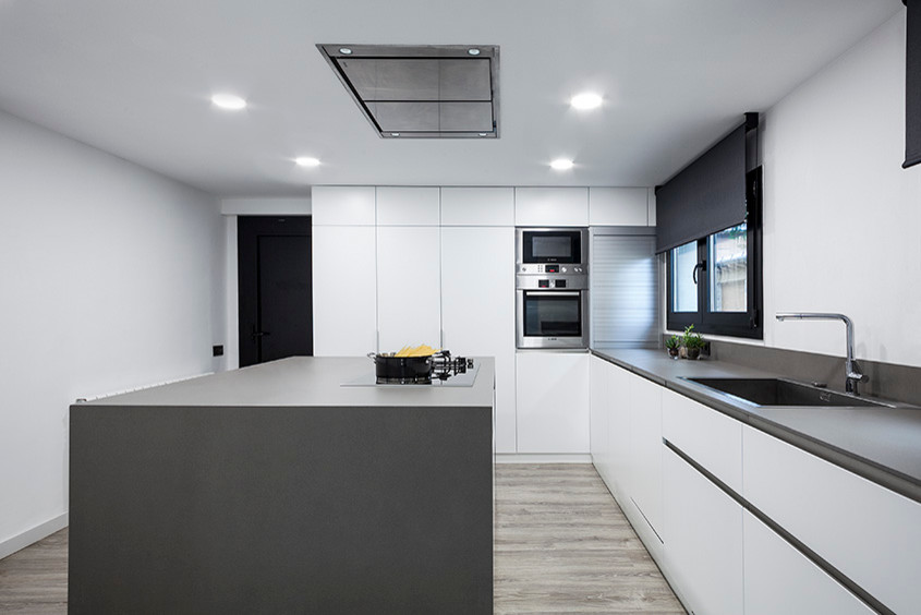 Design ideas for a mid-sized contemporary single-wall separate kitchen in Barcelona with a single-bowl sink, flat-panel cabinets, white cabinets, stainless steel appliances, medium hardwood floors and with island.