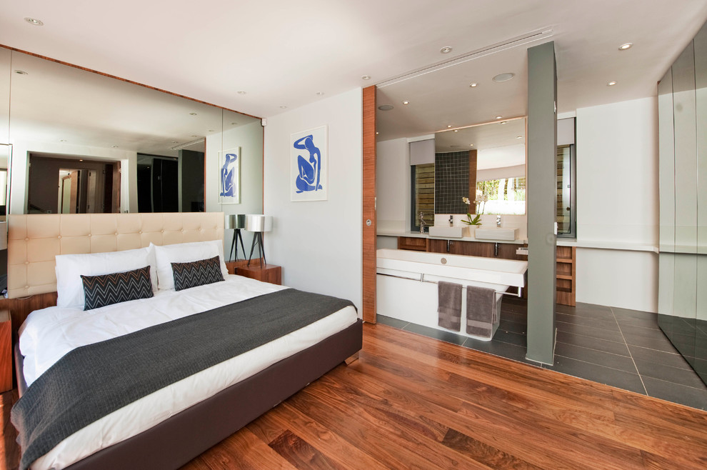 This is an example of a modern bedroom in London with white walls and medium hardwood floors.