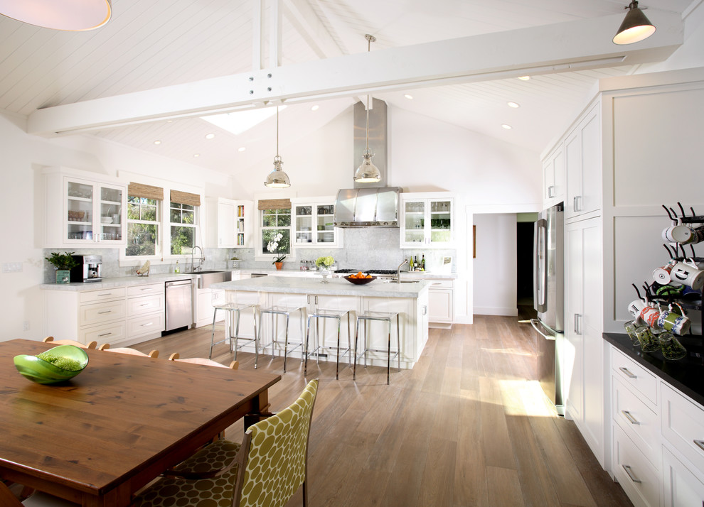 Inspiration for a traditional l-shaped eat-in kitchen in San Francisco with glass-front cabinets, white splashback, stone slab splashback, a farmhouse sink, white cabinets and stainless steel appliances.
