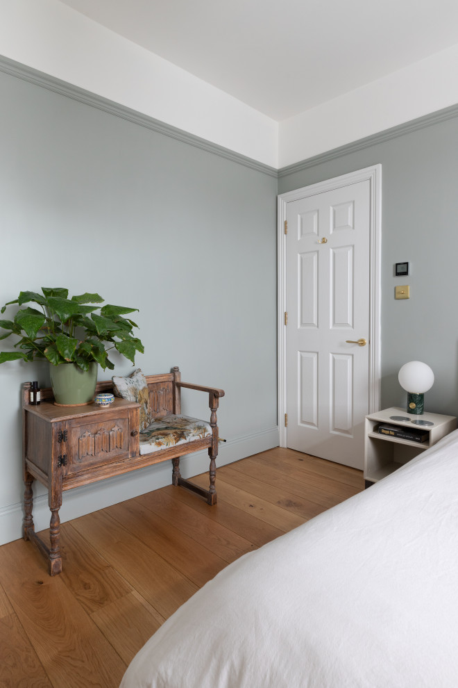 Exemple d'une chambre d'amis tendance de taille moyenne avec un mur vert, un sol en bois brun et un sol marron.
