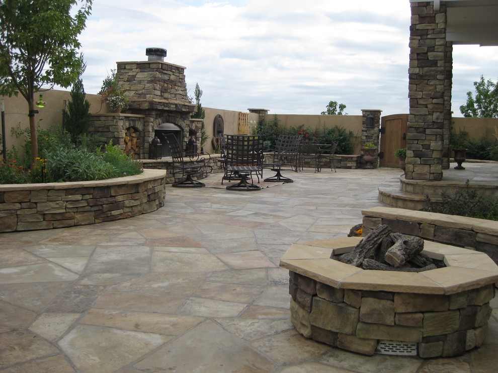 Expansive mediterranean courtyard patio in Denver with with fireplace and natural stone pavers.