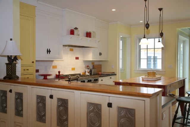 Photo of a mid-sized traditional u-shaped eat-in kitchen in Boston with a farmhouse sink, recessed-panel cabinets, granite benchtops, yellow splashback, porcelain splashback, stainless steel appliances, medium hardwood floors, multiple islands and yellow cabinets.