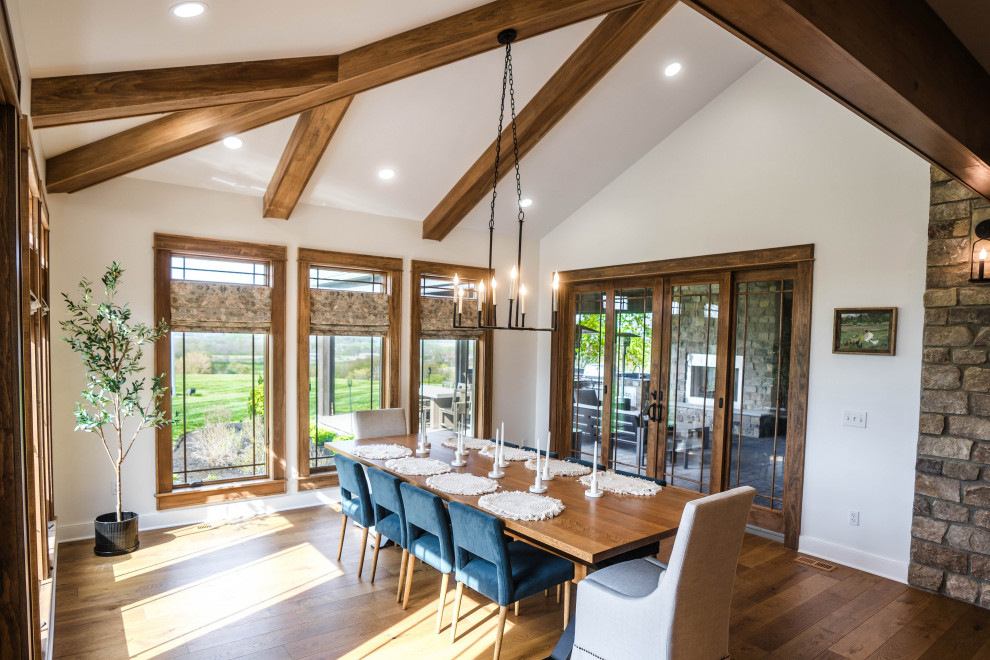 Large transitional light wood floor, brown floor and exposed beam enclosed dining room photo with white walls