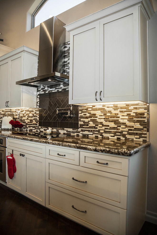 Eat-in kitchen - large transitional l-shaped dark wood floor eat-in kitchen idea in Phoenix with an undermount sink, recessed-panel cabinets, white cabinets, granite countertops, multicolored backsplash, glass tile backsplash, stainless steel appliances and an island