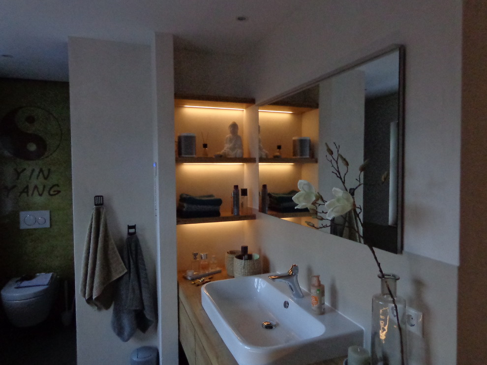 Badezimmer En Suite With flächenbündigen Schrankfronten and hellbraunen Holzschränken in Nuremberg
