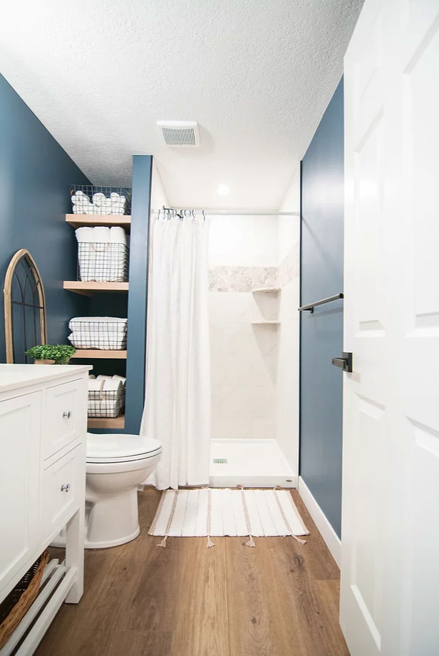 Skandinavisk inredning av ett stort vit vitt badrum med dusch, med skåp i shakerstil, vita skåp, en dusch i en alkov, en toalettstol med hel cisternkåpa, vit kakel, keramikplattor, beige väggar, mellanmörkt trägolv, ett undermonterad handfat, bänkskiva i kvarts, brunt golv och dusch med duschdraperi