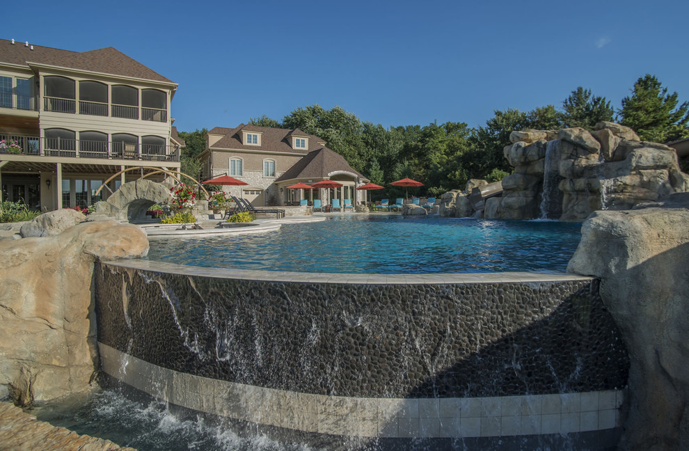 Huge backyard stone and custom-shaped infinity pool fountain photo in Chicago