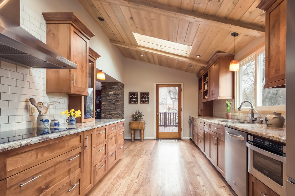 Mountain style galley medium tone wood floor enclosed kitchen photo in Denver with shaker cabinets, medium tone wood cabinets, granite countertops, white backsplash, ceramic backsplash, stainless steel appliances, no island and an undermount sink