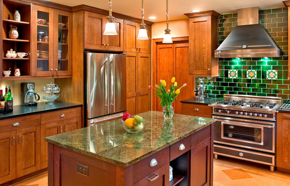 Photo of a large arts and crafts u-shaped separate kitchen in Other with granite benchtops, green splashback, recessed-panel cabinets, medium wood cabinets, stainless steel appliances, cork floors and with island.