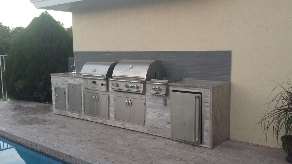 This is an example of a large modern backyard patio in Jacksonville with an outdoor kitchen and no cover.