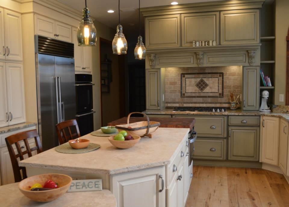 Inspiration for a large traditional u-shaped eat-in kitchen in Cleveland with an undermount sink, raised-panel cabinets, green cabinets, limestone benchtops, multi-coloured splashback, stone tile splashback, stainless steel appliances, light hardwood floors and with island.