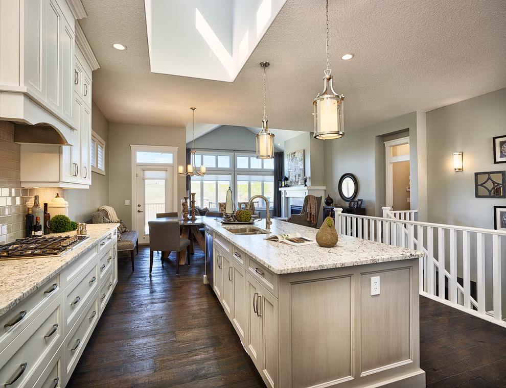 Open concept kitchen - mid-sized transitional l-shaped dark wood floor open concept kitchen idea in Calgary with an undermount sink, recessed-panel cabinets, white cabinets, granite countertops, beige backsplash, ceramic backsplash, stainless steel appliances and an island