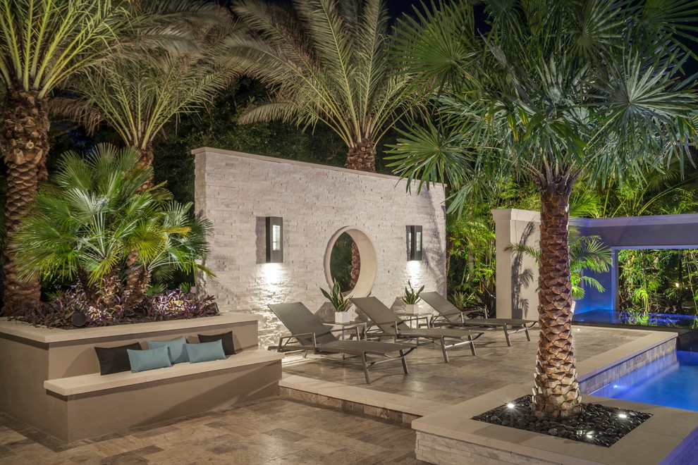 Design ideas for a large modern backyard custom-shaped pool in Tampa with a water feature and natural stone pavers.