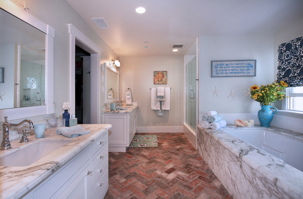 Beach style bathroom in Orange County with an undermount sink, recessed-panel cabinets, white cabinets, an alcove shower, brick floors, an undermount tub and red floor.