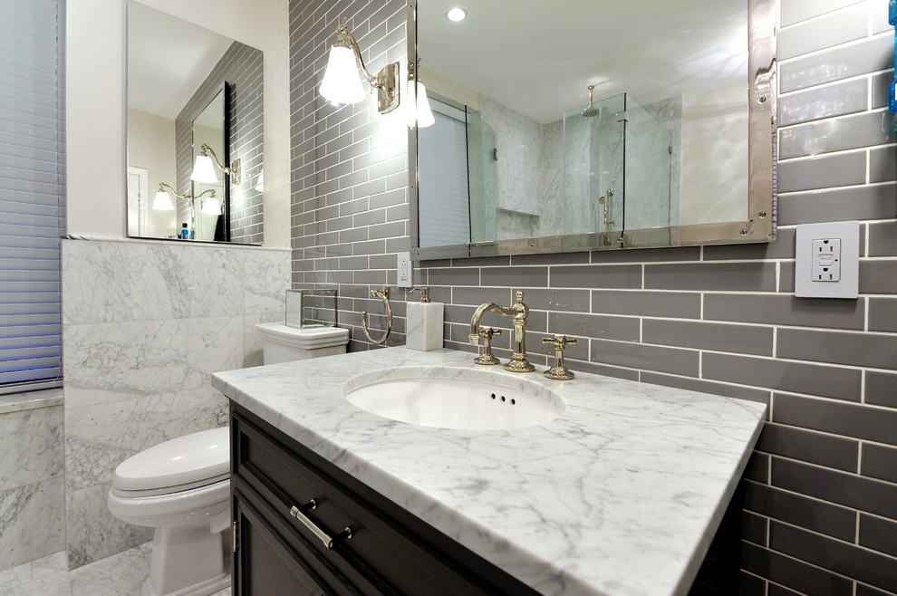 Inspiration for a large contemporary bathroom in New York with an integrated sink, raised-panel cabinets, dark wood cabinets, marble benchtops, a corner tub, a corner shower, a two-piece toilet, gray tile, stone tile, white walls and marble floors.