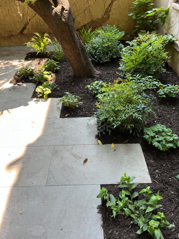 Imagen de jardín moderno pequeño en verano en patio trasero con parterre de flores, exposición reducida al sol, adoquines de piedra natural y con madera