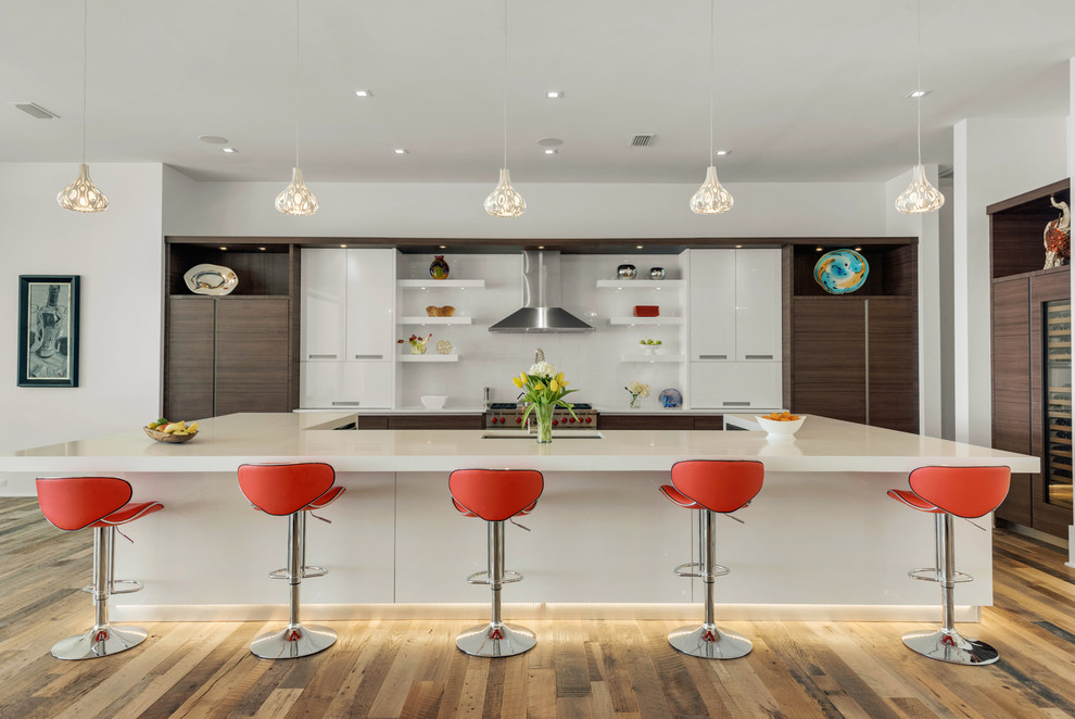 Design ideas for a large contemporary u-shaped open plan kitchen in Miami with an undermount sink, flat-panel cabinets, dark wood cabinets, white splashback, panelled appliances, medium hardwood floors and with island.