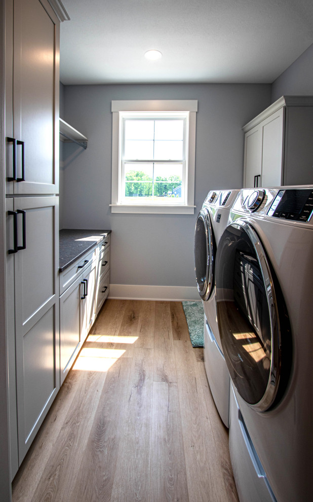 Idéer för små vintage parallella grått tvättstugor enbart för tvätt, med en undermonterad diskho, släta luckor, grå skåp, grå väggar, laminatgolv och en tvättmaskin och torktumlare bredvid varandra