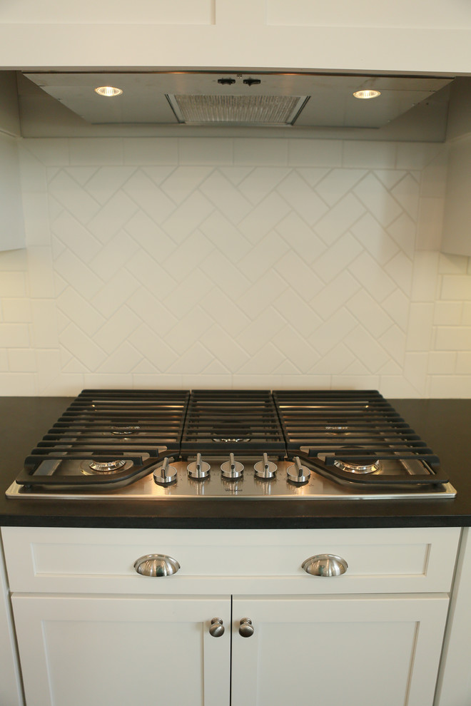 Inspiration for a large transitional u-shaped dark wood floor home design remodel in Chicago with a farmhouse sink, shaker cabinets, yellow cabinets, granite countertops, white backsplash, subway tile backsplash, stainless steel appliances and an island