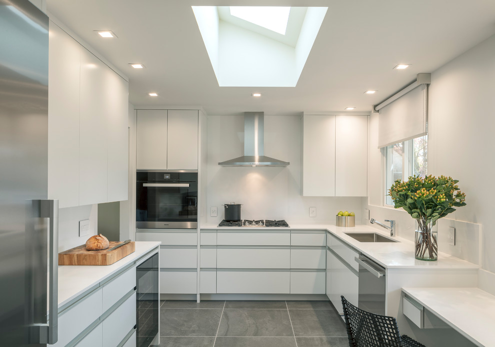 This is an example of a small contemporary u-shaped kitchen in San Francisco with an undermount sink, flat-panel cabinets, white cabinets, quartz benchtops, white splashback, stainless steel appliances, ceramic floors, no island, grey floor and white benchtop.
